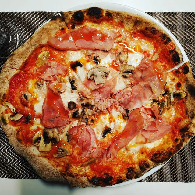 Pizza de jamón cocido y champiñones sobre tomate y mozzarella, vista desde arriba