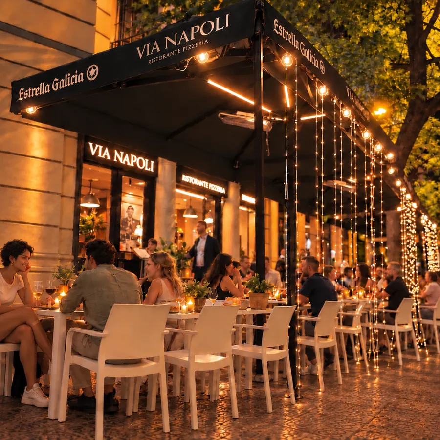 The Via Napoli terrace at night, full, under the awning and the strings of lights